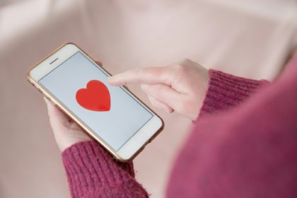 A single girl looking for love by tapping a love heart on her mobile touchscreen online dating app