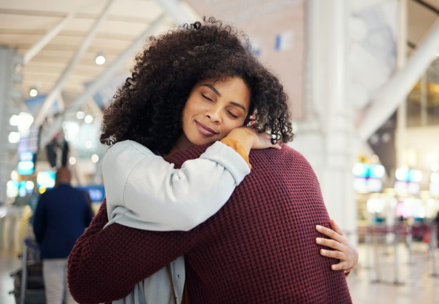 Couple, hug and smile in goodbye at airport for travel, trip or flight in farewell for long distanc